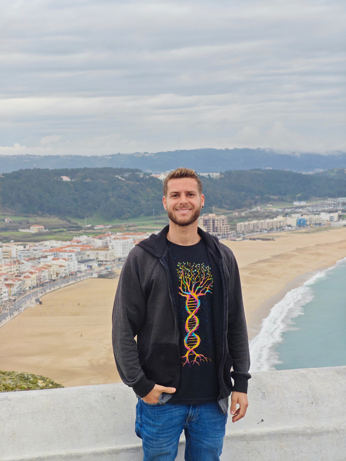 Ilai Levavi standing on a clifftop above a beach town.